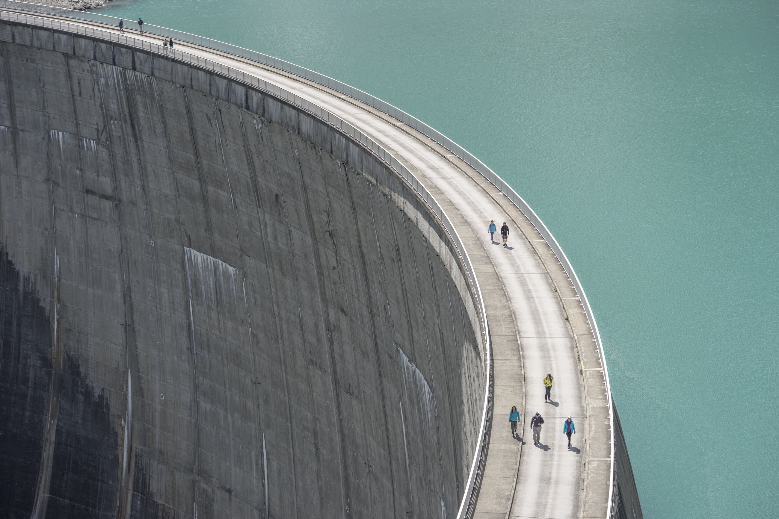 A curved dam wall holding back still water.